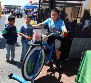 Kid making smoothy by pedaling on a bike.